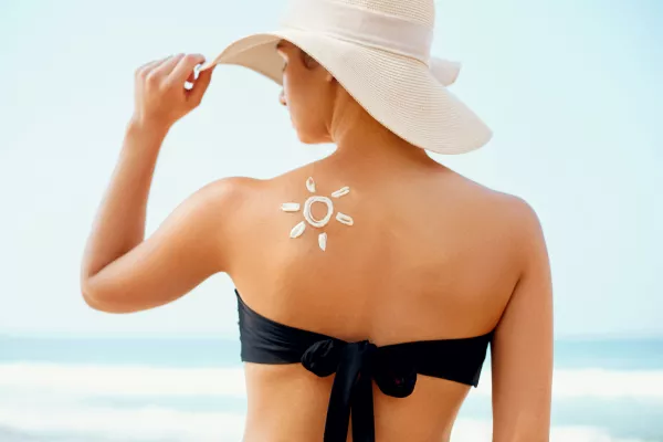 Une personne se protège du soleil avec un chapeau et des lunettes de soleil.