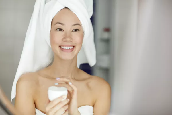 Une femme applique de la crème hydratante